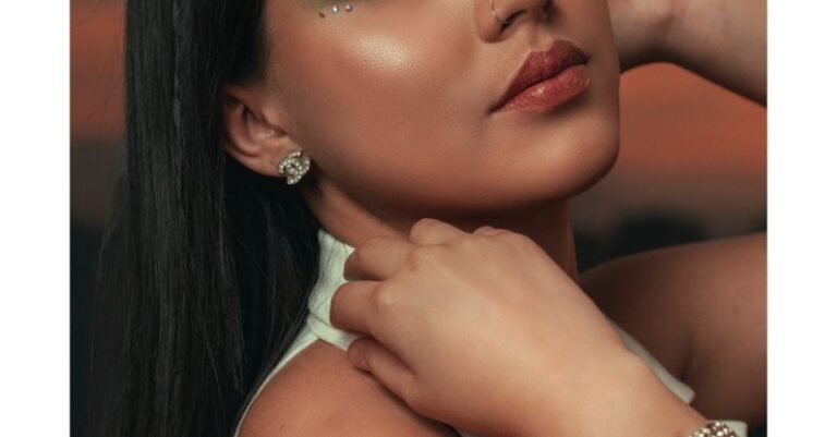 Wearing - A woman with green eyes and jewelry posing for a photo