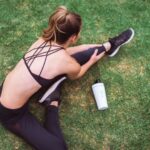 Athleisure - woman in black lingerie holding white bottle