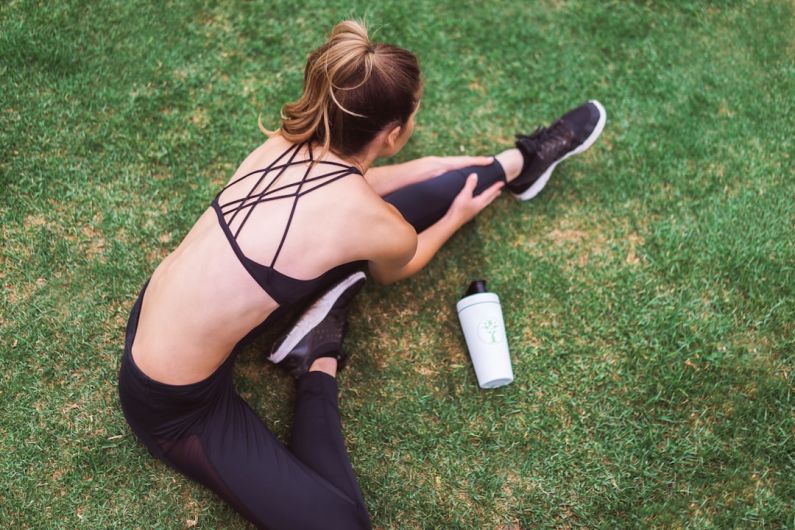 Athleisure - woman in black lingerie holding white bottle