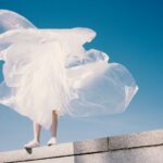 Fashion - person holding plastic while standing on wall