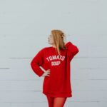 Fashion - woman wearing red long-sleeved shirt standing near white painted wall