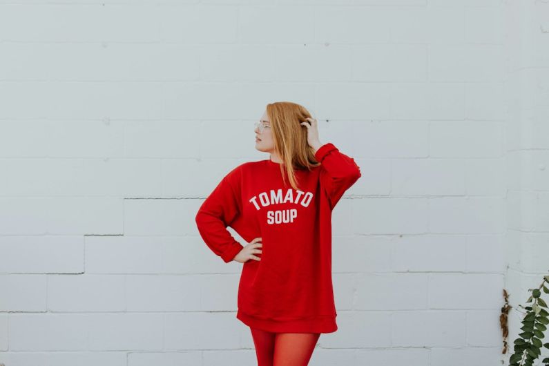 Fashion - woman wearing red long-sleeved shirt standing near white painted wall