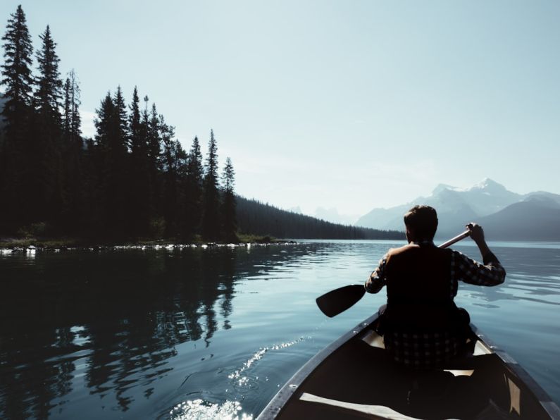 Exploring - man on canoe sailing on the river