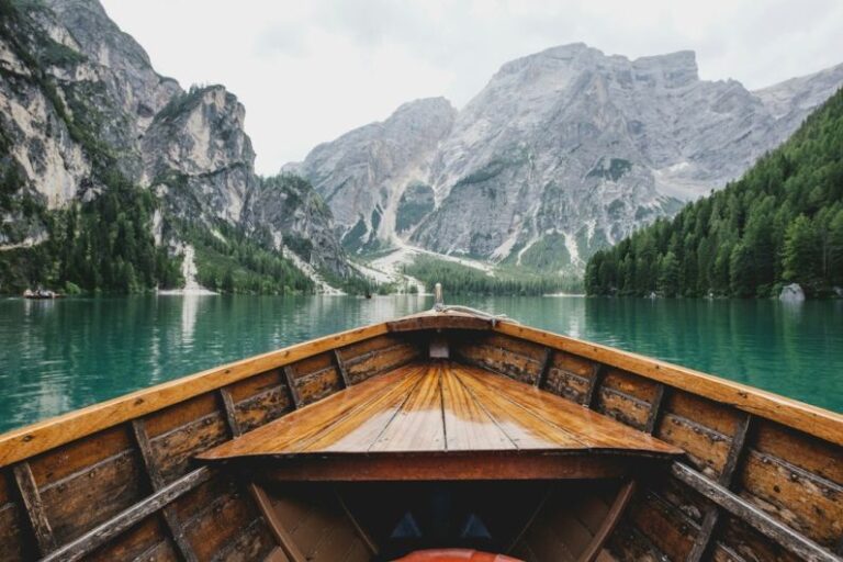 Travel - brown wooden boat moving towards the mountain