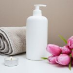 Beauty - white plastic pump bottle beside pink tulips and gray towel