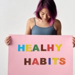 Healthy Habits - Woman Looking at the Pink Poster She's Holding
