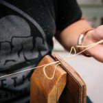 Leather Goods - person in black crew neck t-shirt holding brown wooden guitar pick