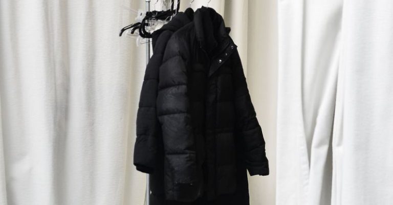 Casual Wardrobe - White curtains and stylish jackets on metal hanger in spacious room at home