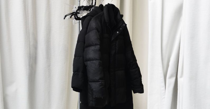 Casual Wardrobe - White curtains and stylish jackets on metal hanger in spacious room at home