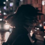 Fashion Moments - Woman in Black Jacket Carrying Backpack With Tousled Hair Walking On The Street At Night