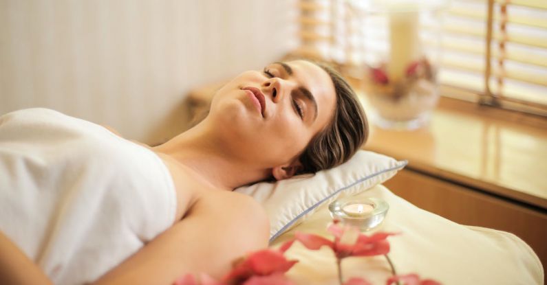 Beauty Treatment - Woman in Wrapped in White Towel Lying on Bed with Eyes Closed