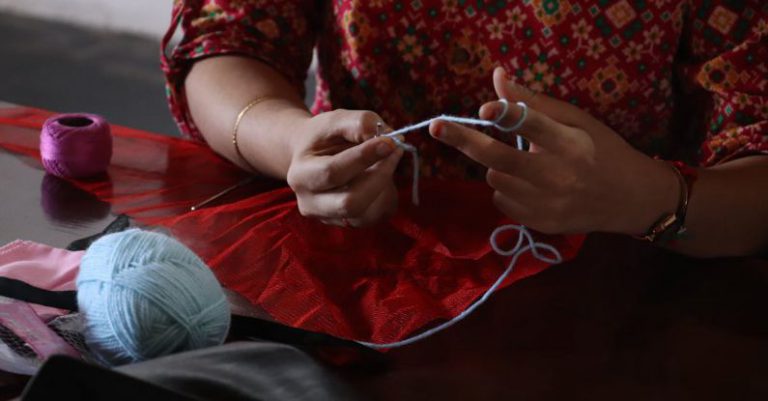 Knitting Basics - A woman is knitting a ball of yarn with a needle