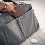 Packing Tips - a person holding a wallet in a bag on a bed