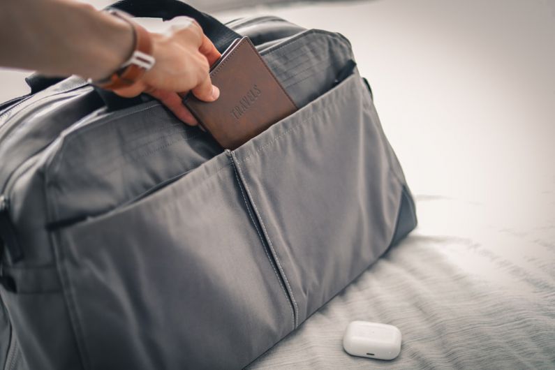 Packing Tips - a person holding a wallet in a bag on a bed