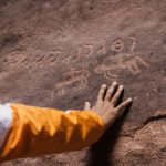 Historical Sites - a person with their hand on a rock