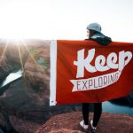 Authentic Travel - person with banner standing on cliff