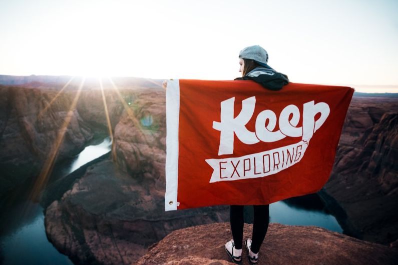 Authentic Travel - person with banner standing on cliff