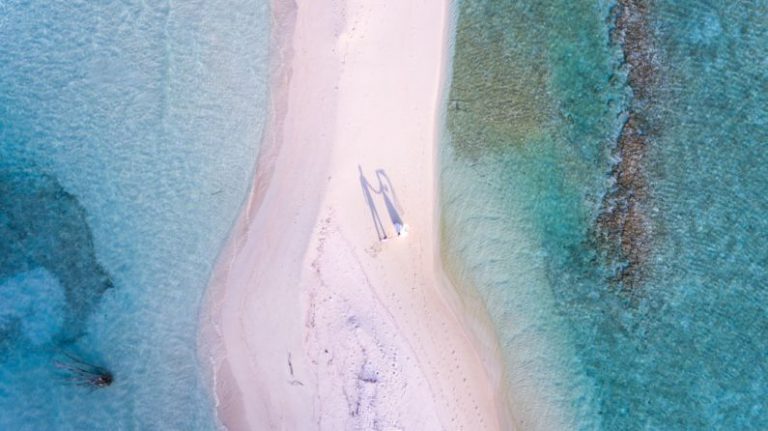 Luxury Budget Travel - aerial photography of couple standing between body of water