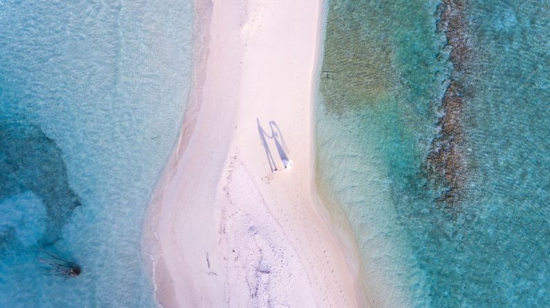 Luxury Budget Travel - aerial photography of couple standing between body of water