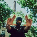 Street Fashion Photography - a person wearing a mask and holding their hands up in front of the eiff