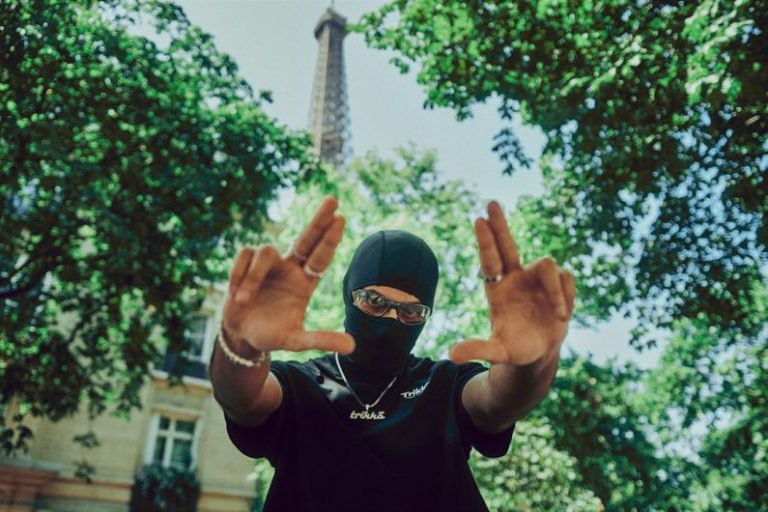 Street Fashion Photography - a person wearing a mask and holding their hands up in front of the eiff