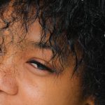 Hairstyle Inspiration - From above of wonderful tender African American woman with small chamomiles blossoms in curly hair looking away