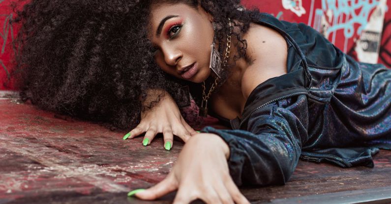 Strong Nails - Beautiful Woman with Long Curly Hair Laying on Garbage Container