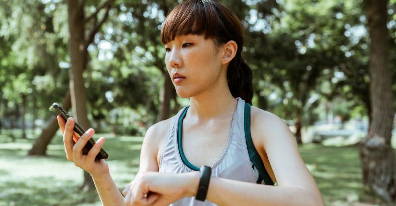 Wellness Apps - Concentrated young Asian woman using smartphone in park